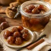 Castañas en almíbar en un tarro de cristal y en un platito con su jarabe, entre hojas de otoño y canela