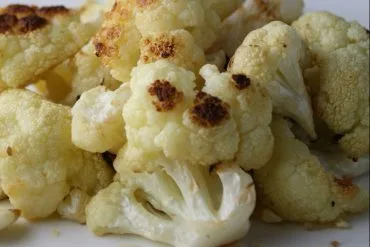 Fuente de coliflor al ajillo gratinada, con las láminas de ajo dorado por encima