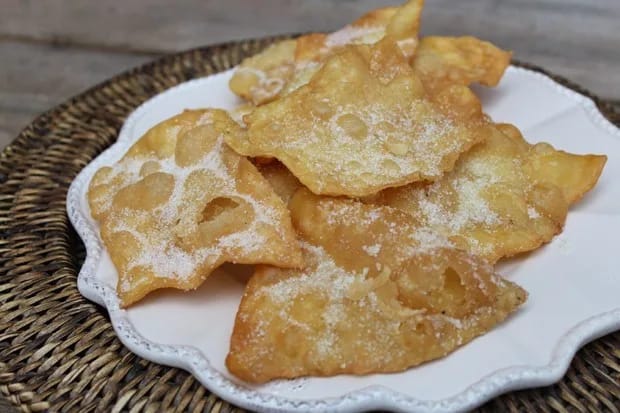Plato de hojuelas castellanas finas y doradas, llenas de ampollas y espolvoreadas con azúcar