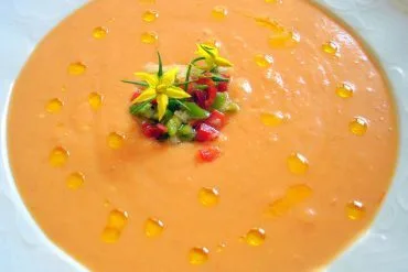 Salmorejo cordobés cremoso y anaranjado con un hilo de aceite de oliva virgen extra y guarnición de verduras