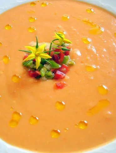 Salmorejo cordobés cremoso y anaranjado con un hilo de aceite de oliva virgen extra y guarnición de verduras