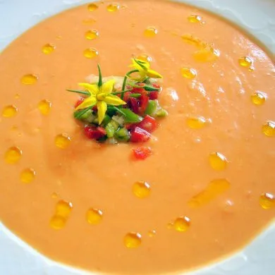 Salmorejo cordobés cremoso y anaranjado con un hilo de aceite de oliva virgen extra y guarnición de verduras