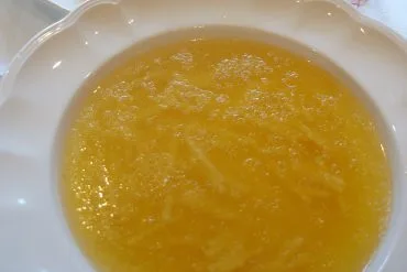 Sopa de cocido con fideos finos en plato blanco, caldo dorado recién servido