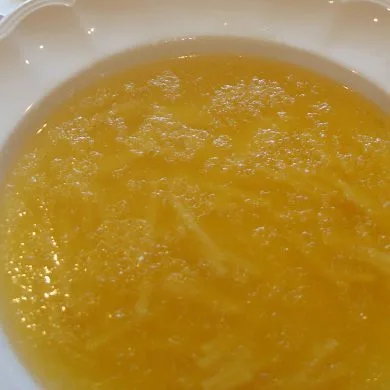 Sopa de cocido con fideos finos en plato blanco, caldo dorado recién servido