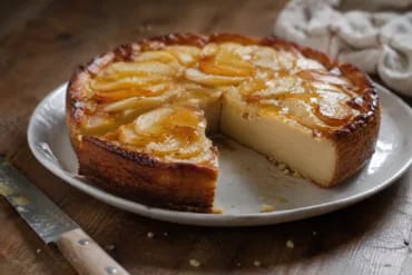 Tarta de manzana y melocotón cortada: el interior es liso y denso, como un flan horneado, con rodajas de fruta pelada en abanico y brillo de mermelada por encima