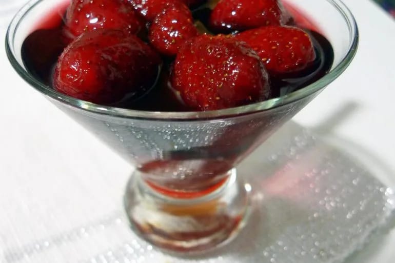 Copa de cristal con fresas enteras maceradas en vino tinto y una rama de canela