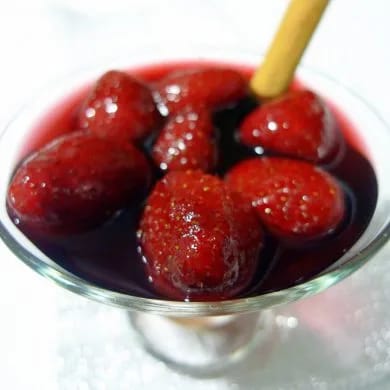 Fresas al vino tinto servidas en copa de cristal con una rama de canela