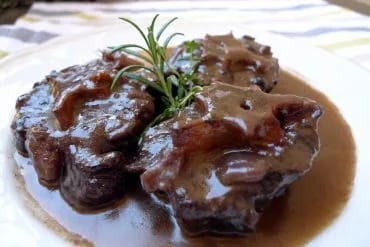 Trozos de rabo de toro tiernos, desprendiéndose del hueso sobre la salsa