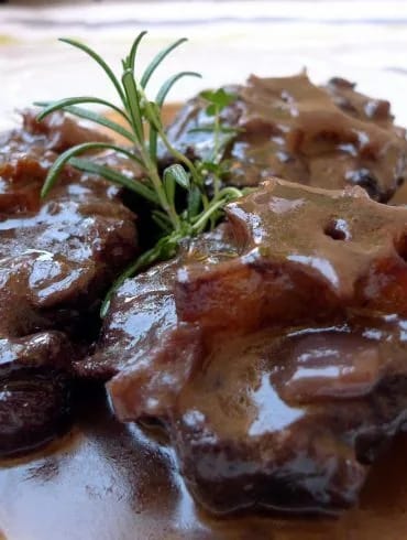 Trozos de rabo de toro tiernos, desprendiéndose del hueso sobre la salsa