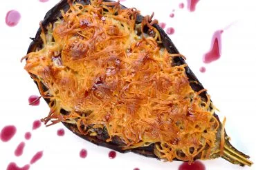 Berenjenas rellenas de carne picada gratinadas con queso, servidas en una fuente de horno