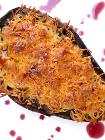 Berenjenas rellenas de carne picada gratinadas con queso, servidas en una fuente de horno