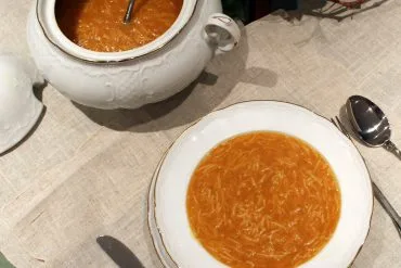 Caldo casero tradicional dorado, servido en un cuenco, base de sopas y guisos