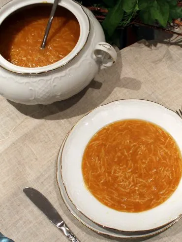 Caldo casero tradicional dorado, servido en un cuenco, base de sopas y guisos