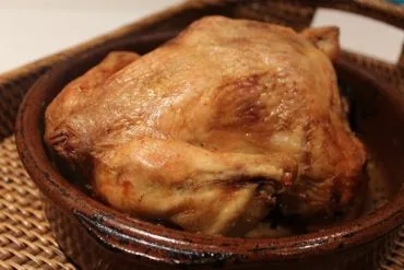 Pollo al horno tradicional dorado en cazuela de barro con su jugo