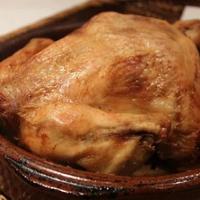 Pollo al horno tradicional dorado en cazuela de barro con su jugo