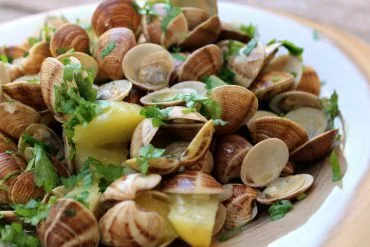 Chirlas al ajillo con patatas servidas en cazuela, con perejil picado