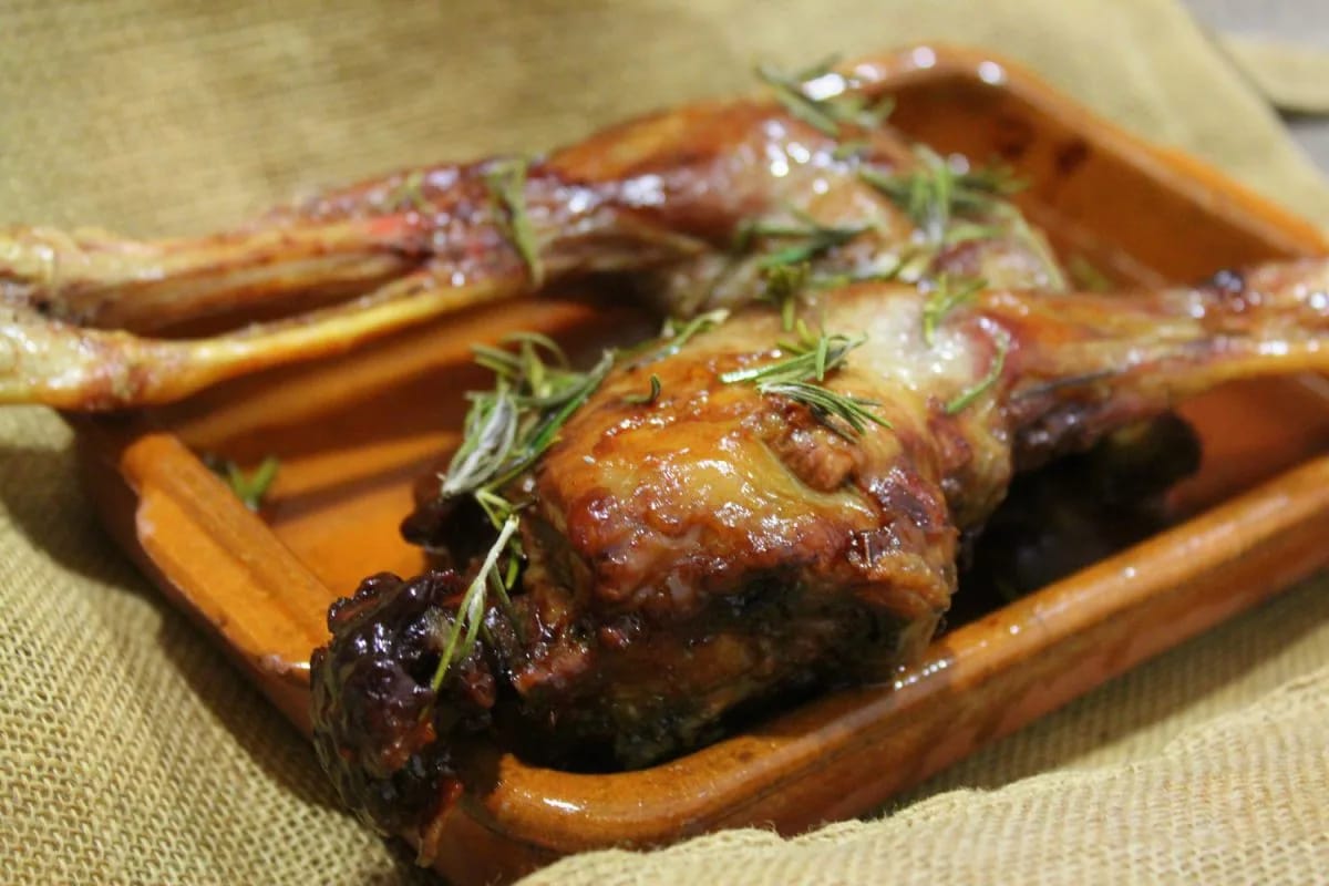 Piernas de cabrito lechal asadas al horno en fuente de barro, con romero y la piel dorada