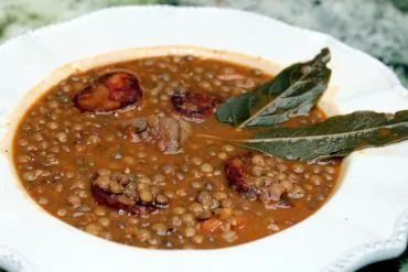 Lentejas con chorizo y panceta servidas en plato hondo