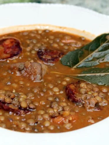 Lentejas con chorizo y panceta servidas en plato hondo