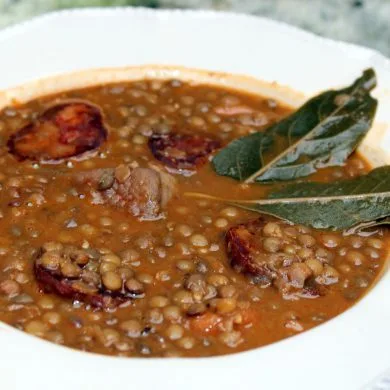Lentejas con chorizo y panceta servidas en plato hondo