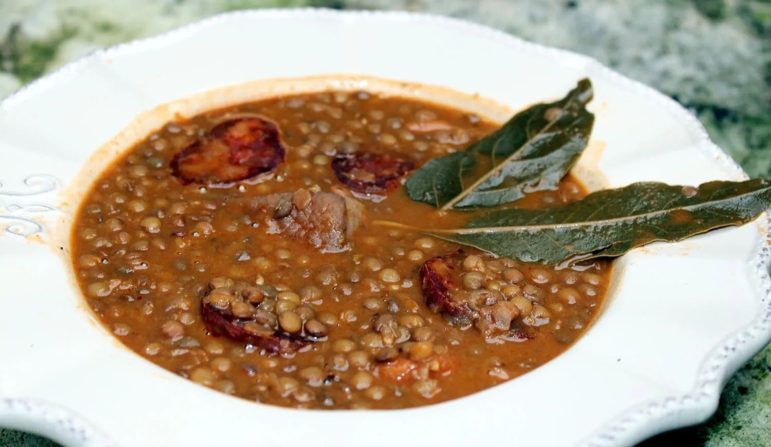 Lentejas con chorizo y panceta servidas en plato hondo