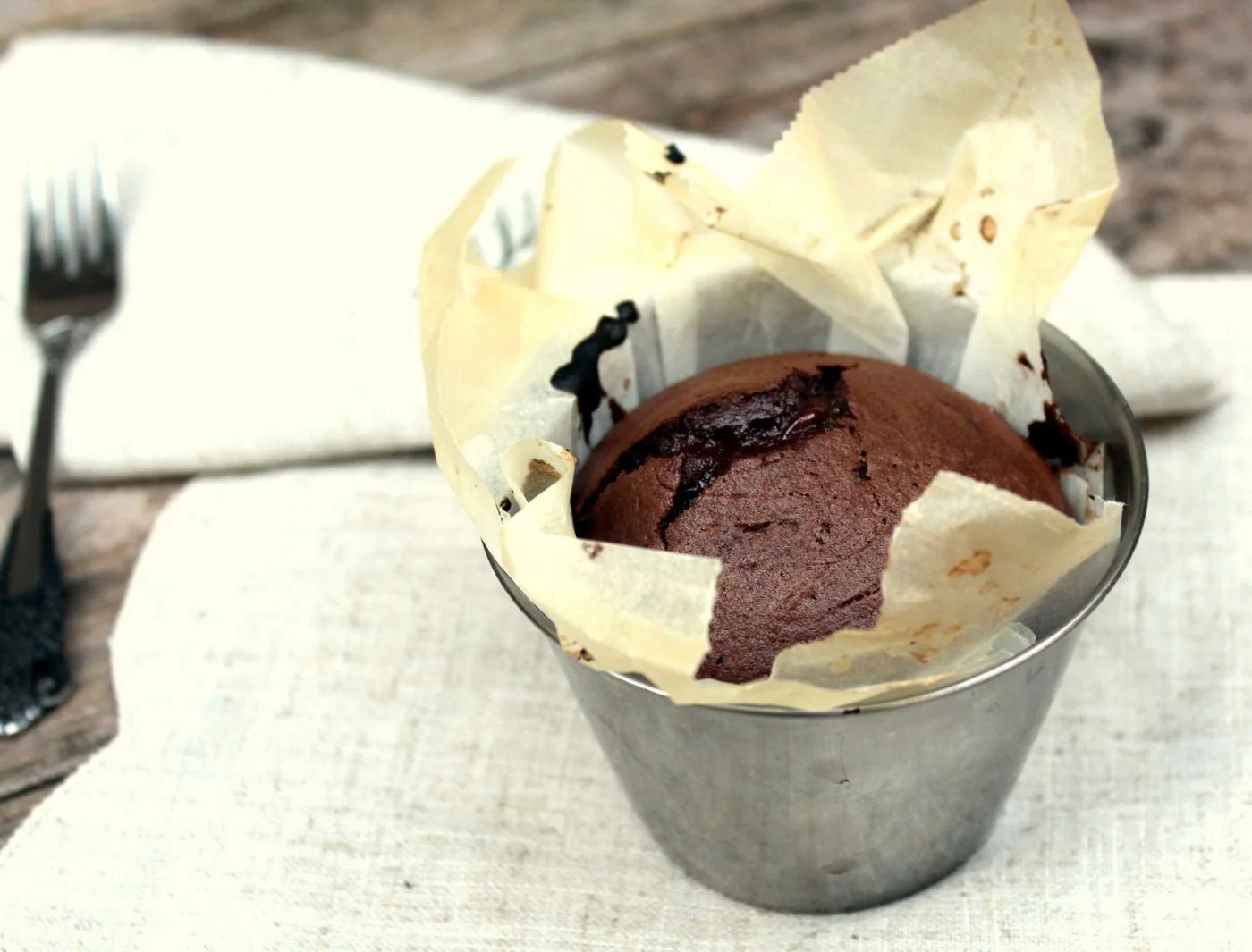 Coulant de chocolate abierto con la cuchara, con el interior fundido derramándose sobre el plato