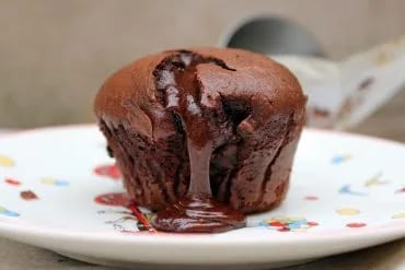 Dos coulants de chocolate servidos, uno entero y otro partido mostrando el corazón líquido