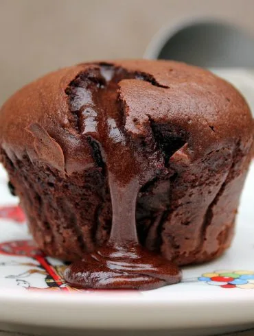 Dos coulants de chocolate servidos, uno entero y otro partido mostrando el corazón líquido