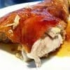 Pierna de cochinillo asada con la piel dorada y crujiente en una fuente