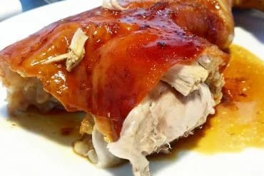 Pierna de cochinillo asada con la piel dorada y crujiente en una fuente
