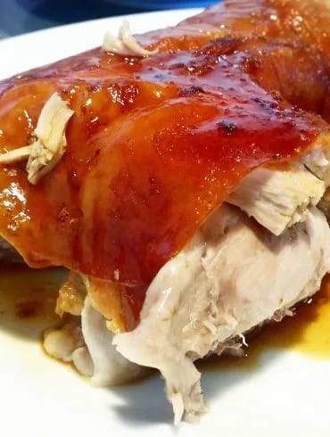 Pierna de cochinillo asada con la piel dorada y crujiente en una fuente