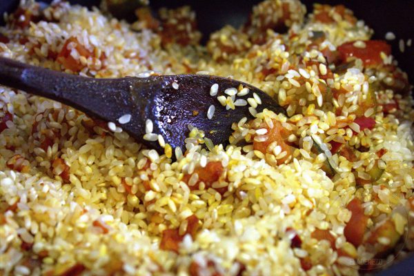 Incorporamos la cebolleta y el pimiento cortado en dados pequeñitos. Pochamos durante cinco minutos a fuego medio-bajo, removiendo de vez en cuando para que no se nos queme.