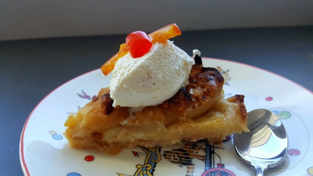 Pudin de roscón de Reyes horneado en su molde ondulado, con las láminas de manzana doradas y las avellanas por encima