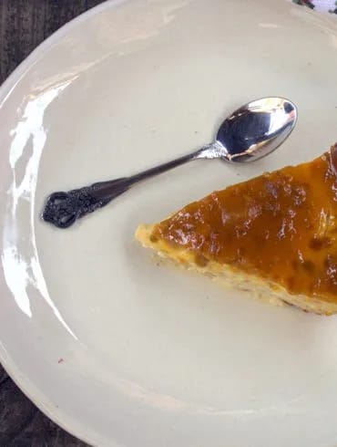 Porción de tarta de queso y mango al horno vista desde arriba, con su cobertura de mermelada y el borde de masa dorado