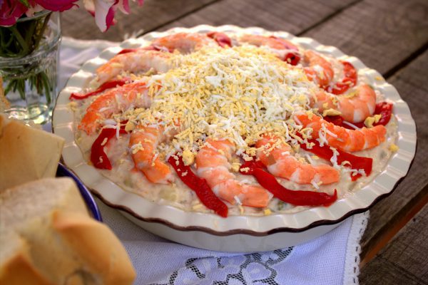 Vertemos sobre un plato o fuente de presentación. Decoramos con las colas de langostinos restantes, unas tiras de pimiento y terminamos rallando el huevo cocido sobre la superficie.