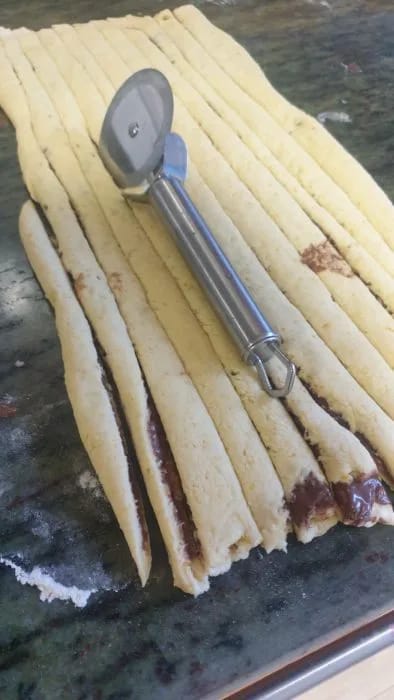 Tira de masa rellena enrollada y anudada a mano para formar el rollo de canela sueco