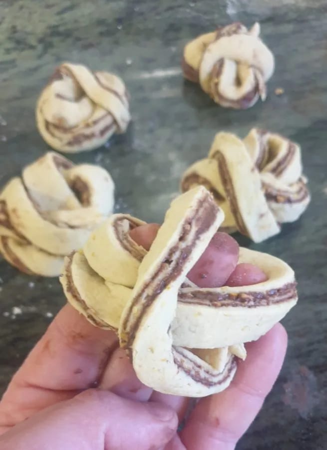 Nudos de masa con Nutella colocados en la bandeja de horno sobre papel de hornear, con espacio entre ellos
