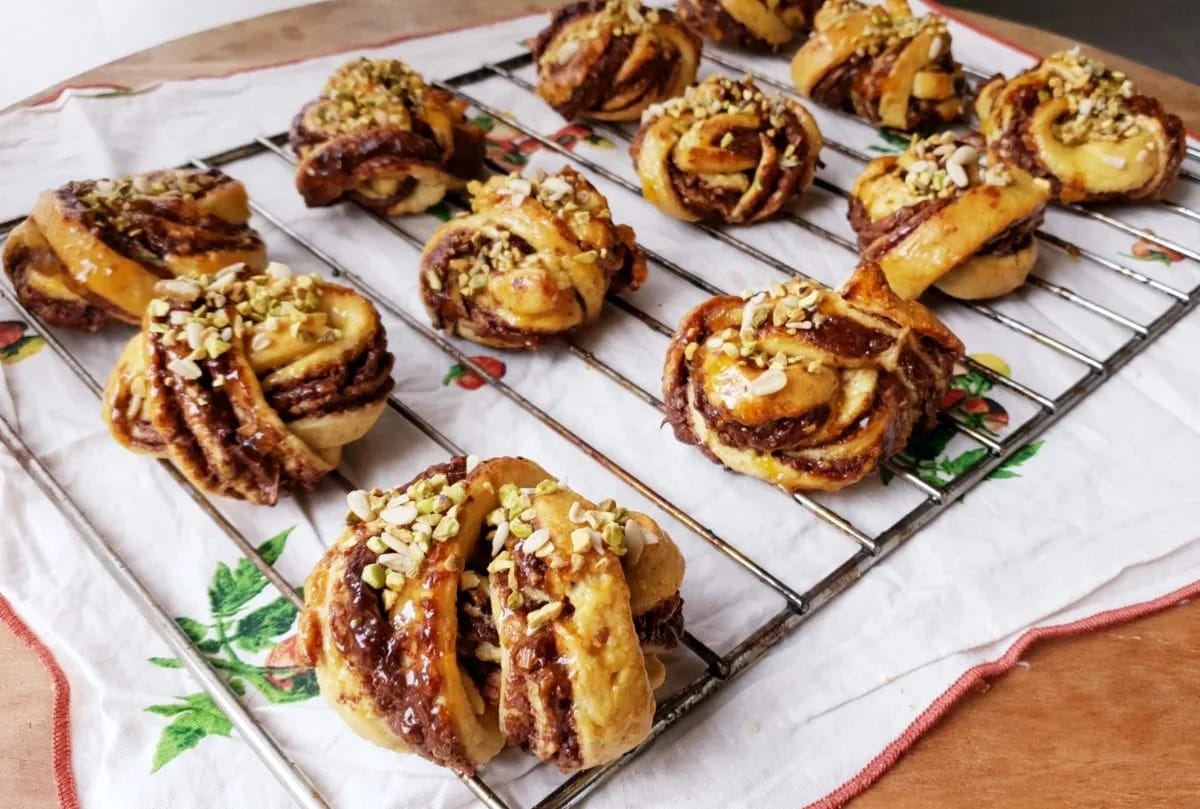 Bandeja de rollos de canela suecos recién horneados con relleno de chocolate y granillo de pistacho por encima