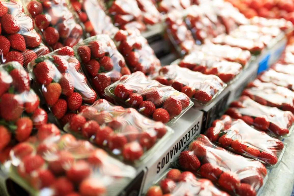 Bandejas de fresas envueltas en plástico en el lineal de un supermercado