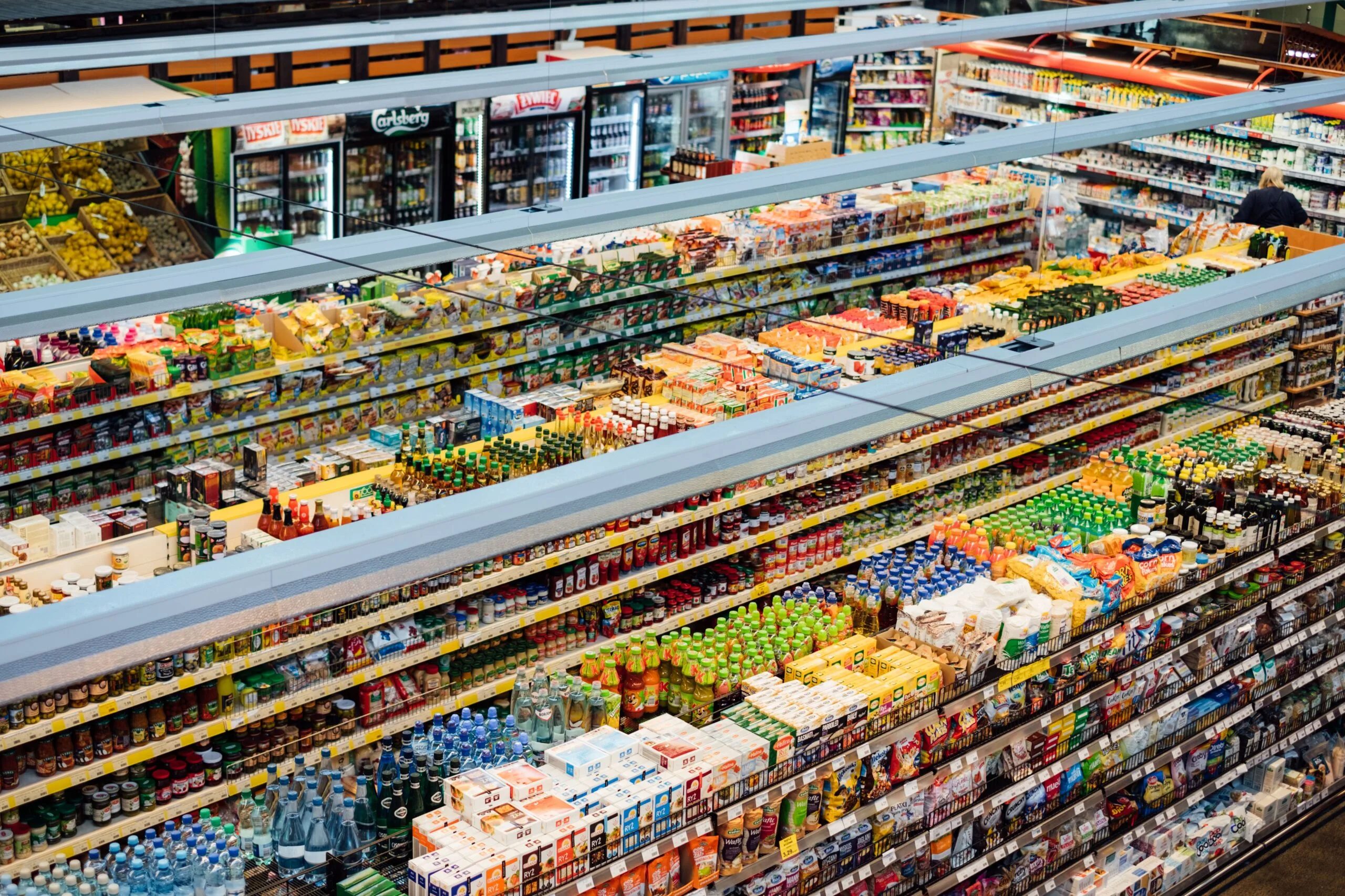Pasillo de supermercado visto desde arriba, con los lineales llenos de productos envasados
