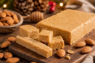 Turrón blando casero de almendra y miel en trozos sobre una tabla de madera